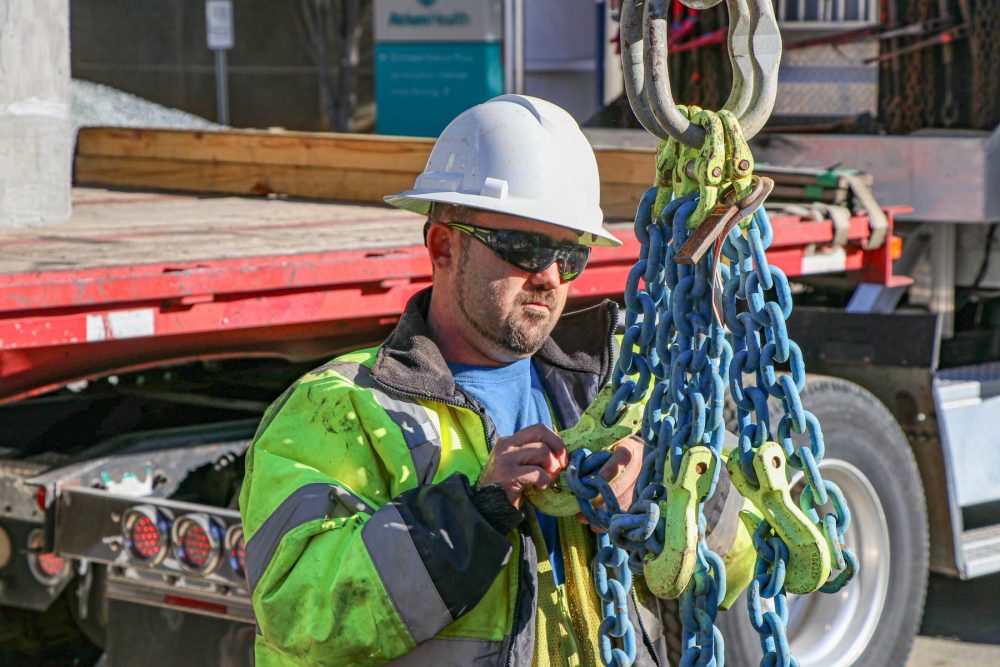 HALL employee wearing white helmet holding onto blue and yellow chains