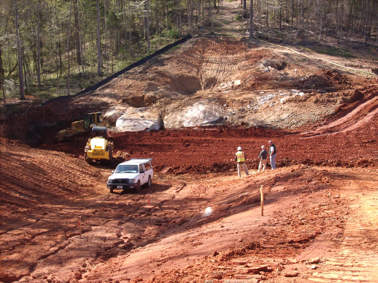 The Alex Porter Dam begins to have fresh red dirt compacting onto it by HALL employees